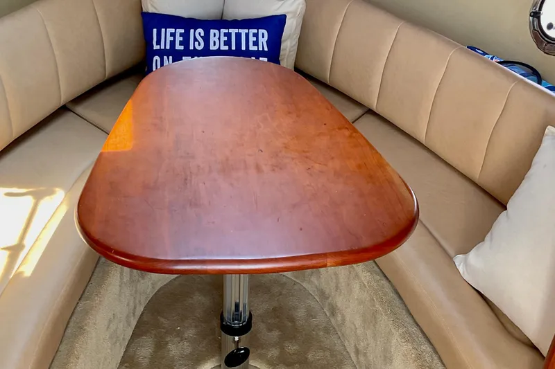 Slide: The Image of Interior of 2013 Rinker 290 Express Cruiser with wooden table and cushioned seating. - 16