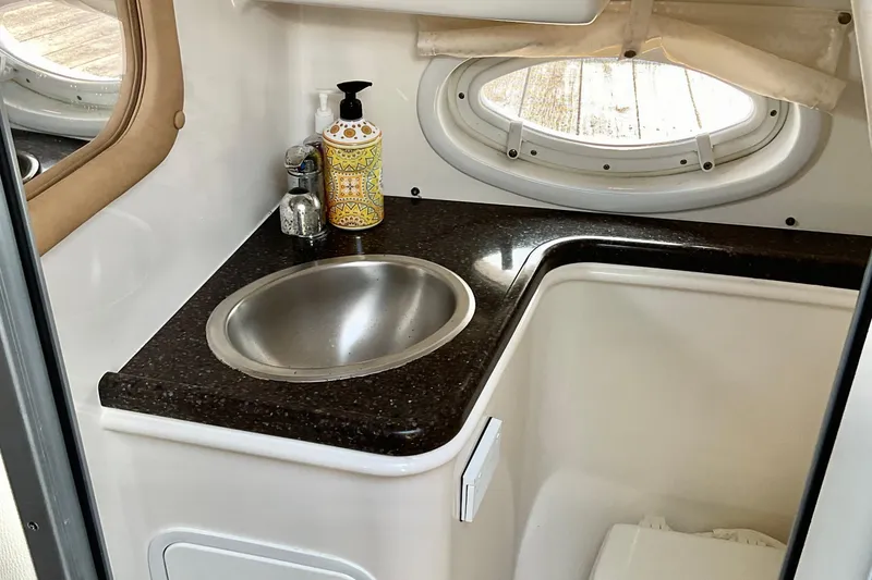Slide: The Image of 2013 Rinker 290 Express Cruiser bathroom with sink, countertop, and porthole window. - 19
