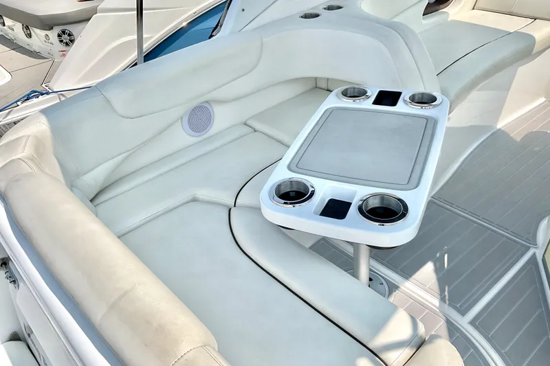 Slide: The Image of 2013 Rinker 290 Express Cruiser interior with white seating and cupholder table. - 5