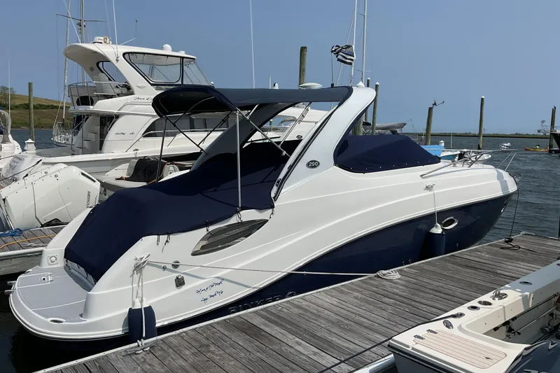 Slide: The Image of 2013 Rinker 290 Express Cruiser docked at marina, covered with navy blue canvas. - 8