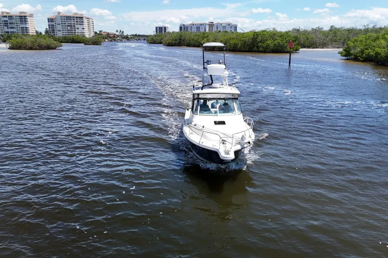 Slide: The Image of 2007 Pursuit OS 285 Offshore boat cruising on a scenic waterway with buildings in the background. - 10