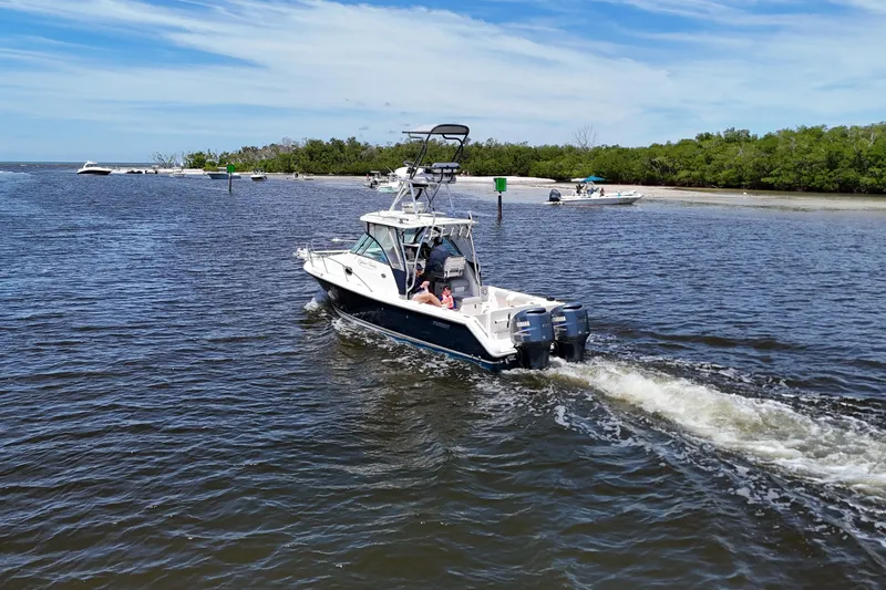 Slide: The Image of 2007 Pursuit OS 285 Offshore boat cruising on a sunny day near a shoreline. - 12