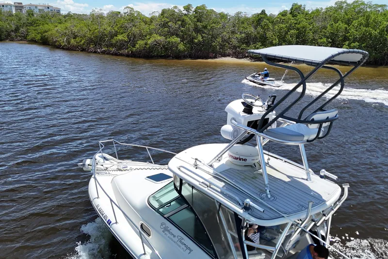 Slide: The Image of 2007 Pursuit OS 285 Offshore boat cruising near a jet ski on a scenic waterway. - 19
