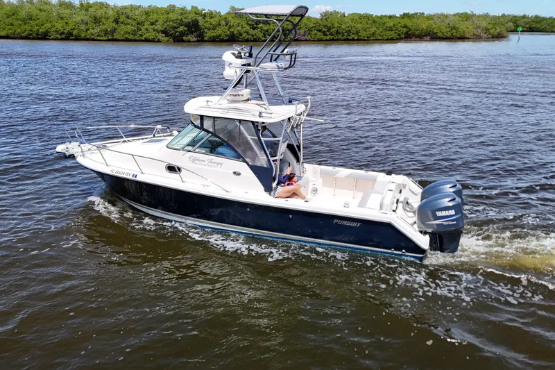 Slide: The Image of 2007 Pursuit OS 285 Offshore boat cruising on a calm river with lush greenery. - 2