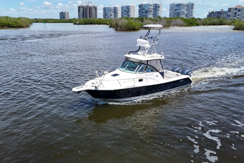 Slide: The Image of 2007 Pursuit OS 285 Offshore boat cruising on a river with cityscape background. - 3