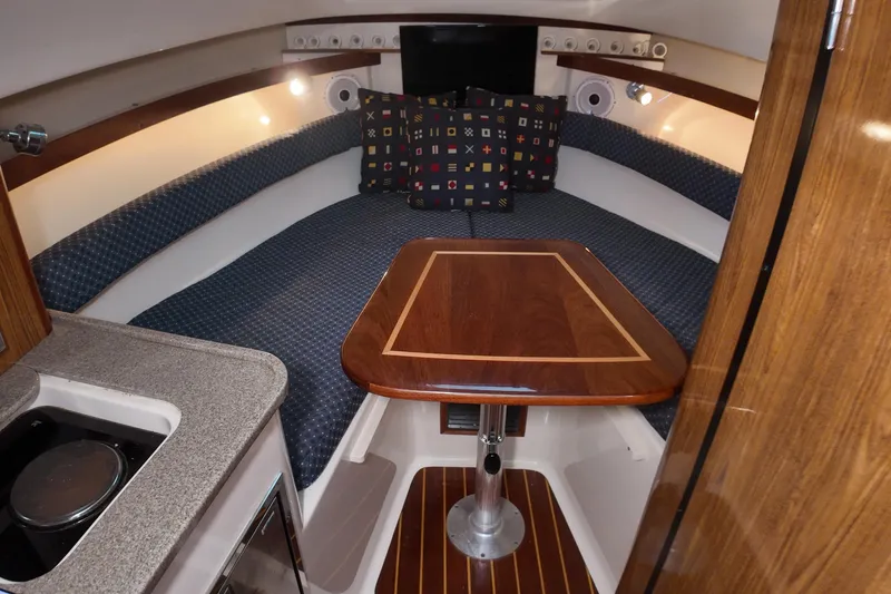 Slide: The Image of 2007 Pursuit 285 Offshore cabin interior with wooden table and cushioned seating. - 31