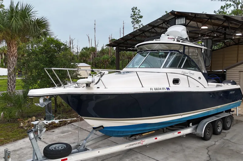 Slide: The Image of 2007 Pursuit 285 Offshore boat on trailer, parked outdoors near palm trees. - 37