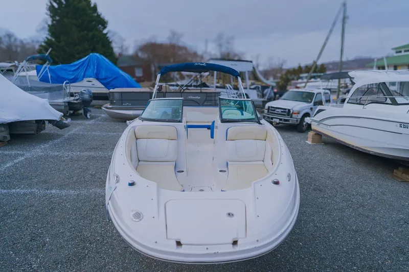 Slide: The Image of 2013 Sea Ray 240 Sundancer boat in a marina, surrounded by other vessels. - 7