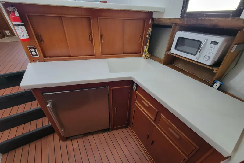 Slide: The Image of Compact kitchen area in a 1992 Mediterranean 38 boat with wooden cabinets and modern appliances. - 4