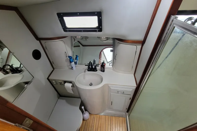 Slide: The Image of Compact bathroom in a 1992 Mediterranean 38 boat, featuring a sink, mirror, and shower. - 6