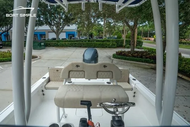 Slide: The Image of 2024 Sea Pro 208 Bay boat interior with seating and steering wheel, parked outdoors. - 13