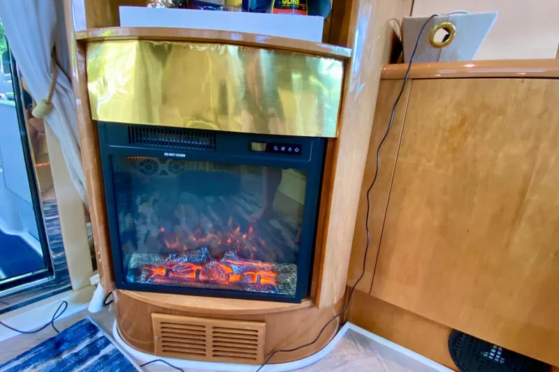 Slide: The Image of Electric fireplace in 1999 Neptunus 54 Hardtop Express yacht interior, featuring wood and gold accents. - 31