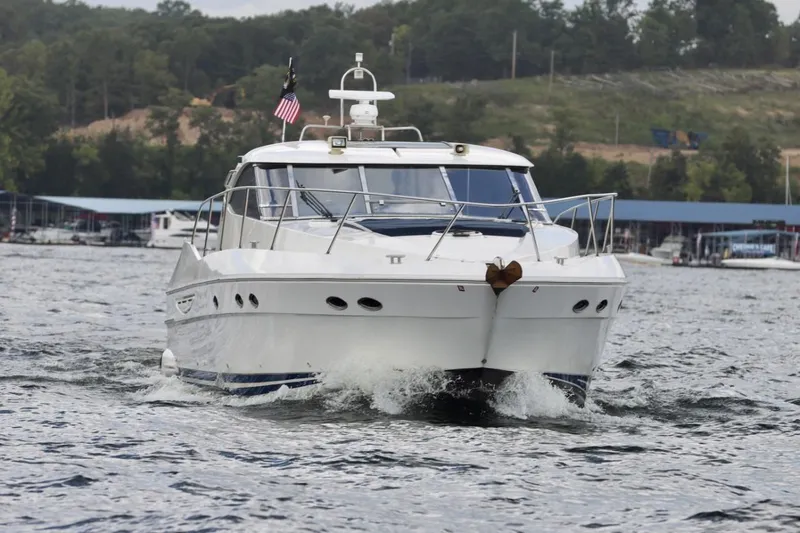 Slide: The Image of 1999 Neptunus 54 Hardtop Express yacht cruising on a lake with marina backdrop. - 6