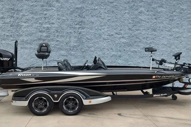 Slide: The Image of 2015 Triton 21 TrX bass boat with dual axle trailer, parked on concrete. - 1
