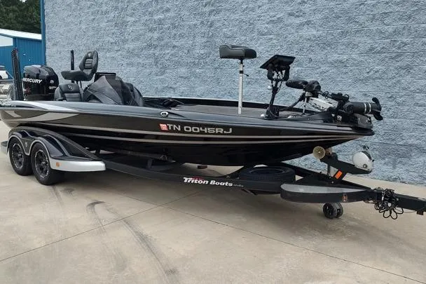 Slide: The Image of 2015 Triton 21 TrX bass boat on trailer, parked outdoors. - 2