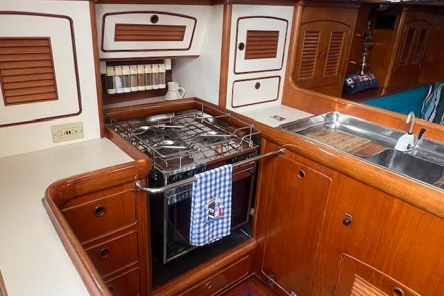 Slide: The Image of 1986 Little Harbor AFt Cockpit K/CB Sloop kitchen with stove, sink, and wooden cabinetry. - 12