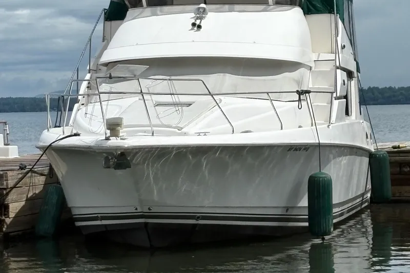 The Image of 1999 Silverton 392 yacht docked at a marina, reflecting sunlight on calm water. - 0