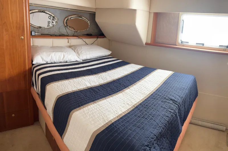 Slide: The Image of Cozy bedroom in 1999 Silverton 392 yacht with striped bedding and porthole window. - 14