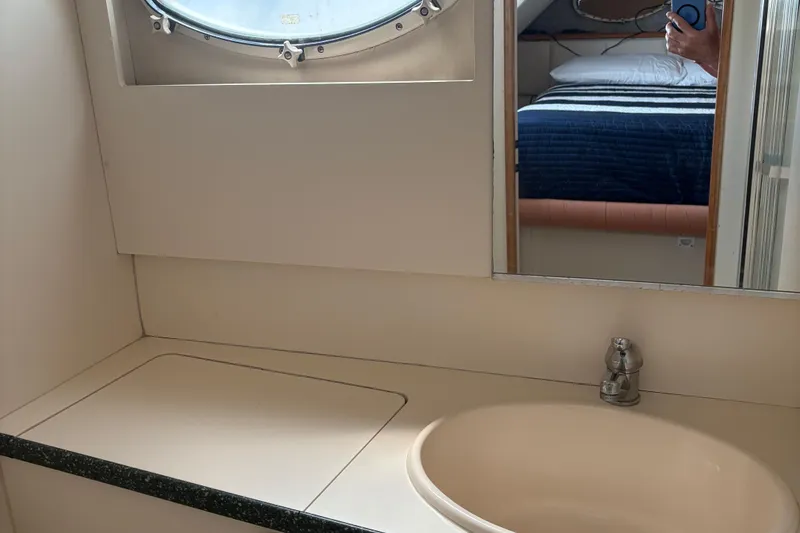 Slide: The Image of Bathroom interior of 1999 Silverton 392 yacht with sink, mirror, and porthole window. - 17