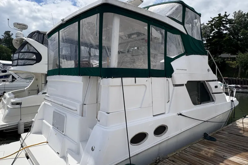 Slide: The Image of 1999 Silverton 392 yacht docked, featuring green canvas enclosure and sleek white design. - 2