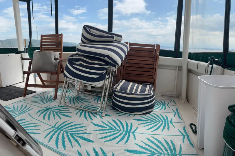 Slide: The Image of 1999 Silverton 392 boat deck with striped cushions, wooden chairs, and a tropical-patterned rug. - 33