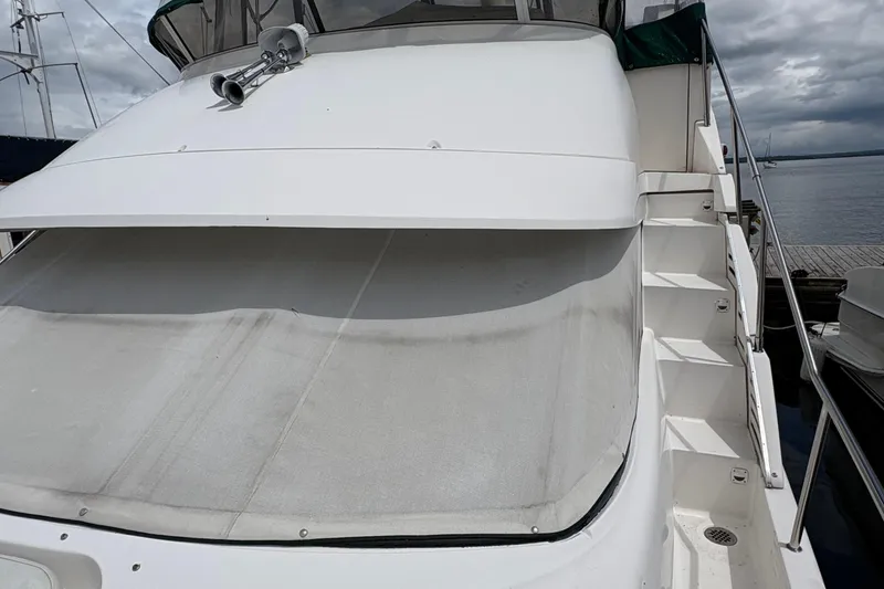 Slide: The Image of 1999 Silverton 392 yacht with covered deck and side stairs, docked by the water. - 39