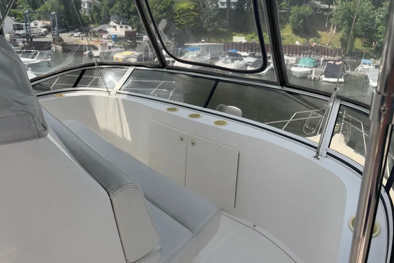 Slide: The Image of 1999 Silverton 392 yacht interior with marina view, featuring white seating and large windows. - 7