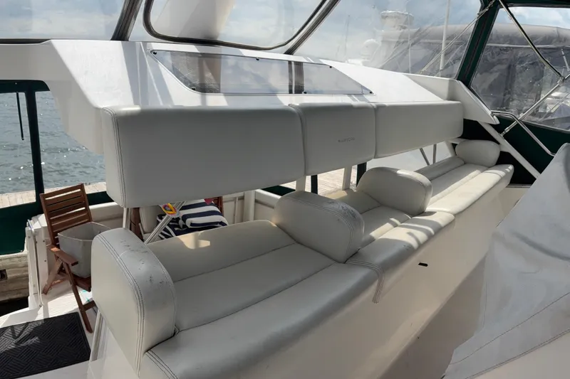 Slide: The Image of Interior of a 1999 Silverton 392 yacht with white seating and wooden chairs. - 8