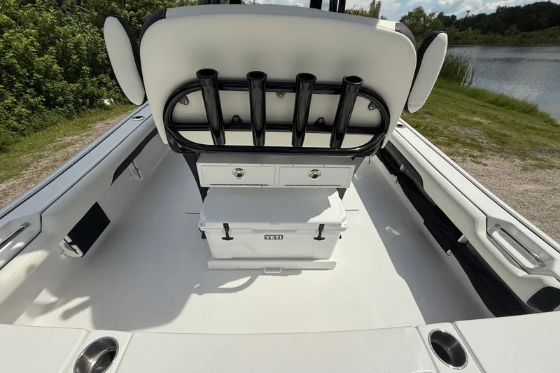 Slide: The Image of 2026 Tidewater 2500 Carolina Bay boat interior with rod holders and storage, near a lake. - 16