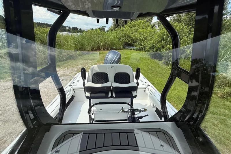 Slide: The Image of 2026 Tidewater 2500 Carolina Bay boat interior with dual seats and lush greenery backdrop. - 24