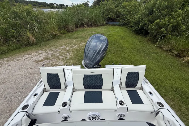 Slide: The Image of 2026 Tidewater 2500 Carolina Bay boat with seating and outboard motor, surrounded by greenery. - 27