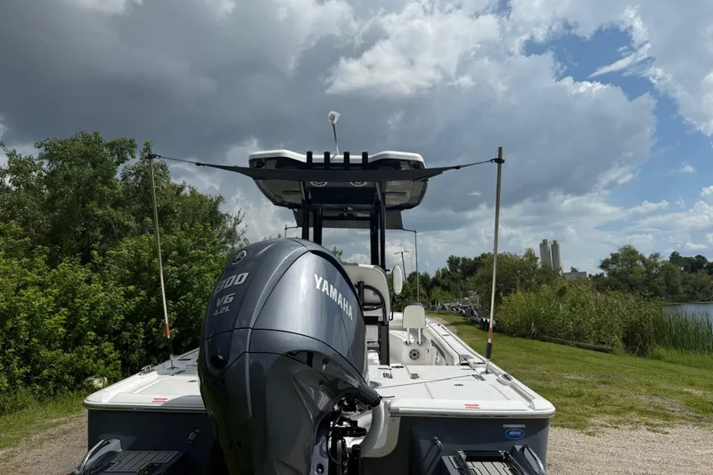 Slide: The Image of 2026 Tidewater 2500 Carolina Bay boat with Yamaha engine, parked near lush greenery under cloudy sky. - 49