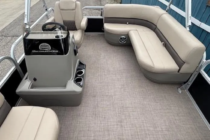 Slide: The Image of 2024 Sun Tracker Party Barge 16 DLX interior with beige seating and steering console. - 11