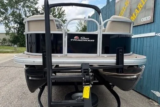 Slide: The Image of 2024 Sun Tracker Party Barge 16 DLX pontoon boat on trailer, parked outdoors. - 2