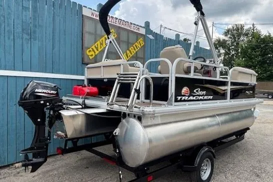 Slide: The Image of 2024 Sun Tracker Party Barge 16 DLX pontoon boat with Mercury outboard motor, parked on trailer. - 3
