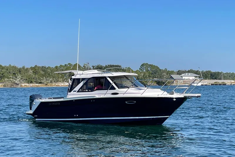 The Image of 2026 Cutwater C-248 Coupe boat cruising on a calm lake under a clear blue sky. - 0
