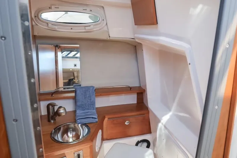 Slide: The Image of 2026 Cutwater C-248 Coupe interior bathroom with sink, mirror, and wooden cabinetry. - 15