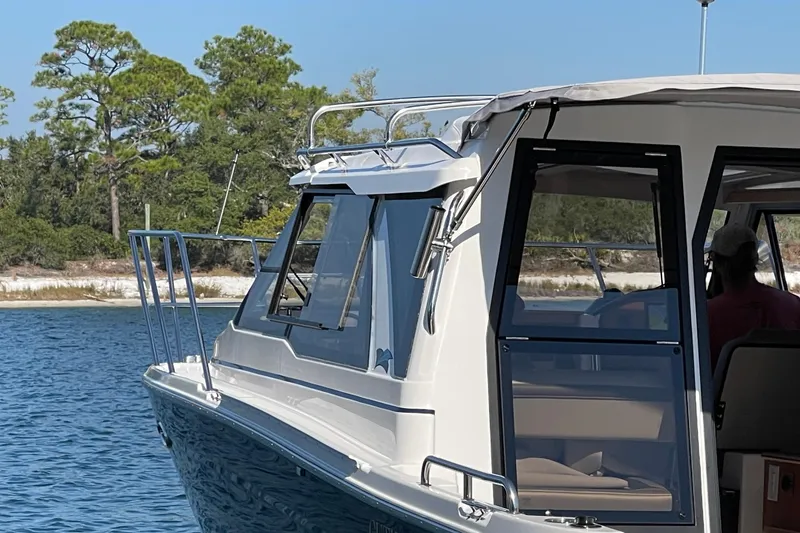 Slide: The Image of 2026 Cutwater C-248 Coupe boat on water, near a forested shoreline. - 3