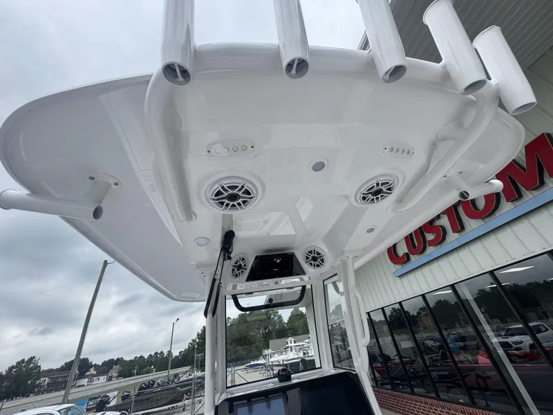 Slide: The Image of 2026 Sportsman Masters 247OE Bay Boat T-top with speakers and rod holders, outdoor display. - 32