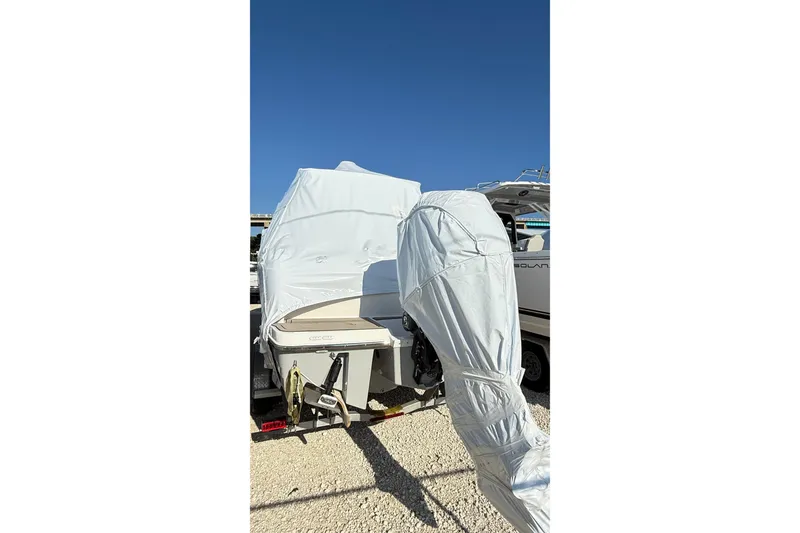 Slide: The Image of 2026 Cutwater C-248 Coupe boat covered in protective wrap, parked on gravel. - 19
