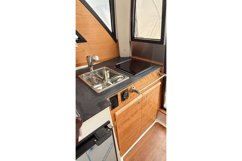 Slide: The Image of 2026 Cutwater C-248 Coupe interior kitchen with sink, stove, and wooden cabinetry. - 34