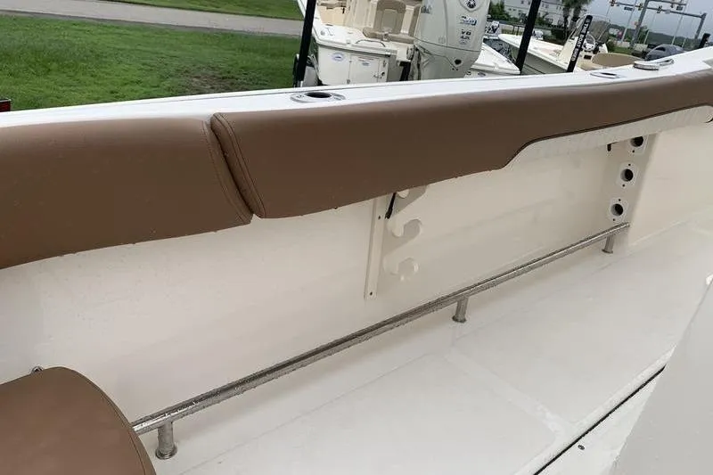 Slide: The Image of 2025 Pionee Sportfish 222 boat interior with brown cushioned seating and rod holders. - 24