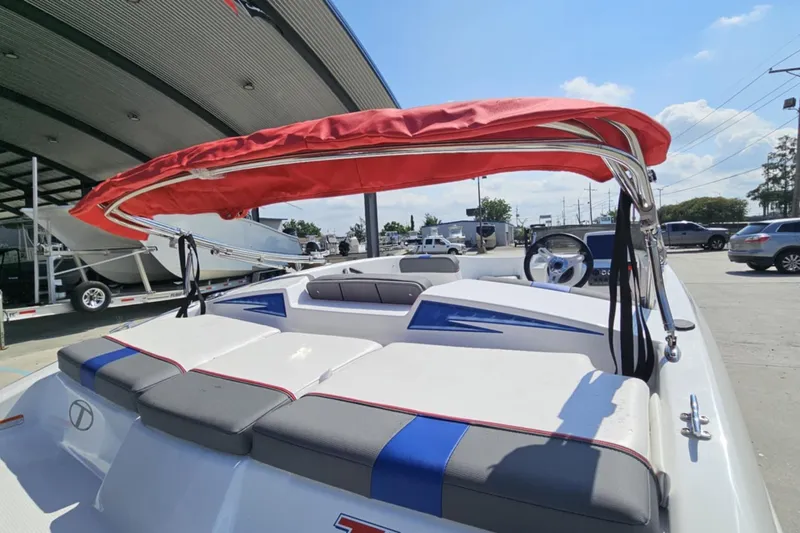 Slide: The Image of 2024 Tahoe T16 boat with red canopy, parked outdoors under a clear blue sky. - 9