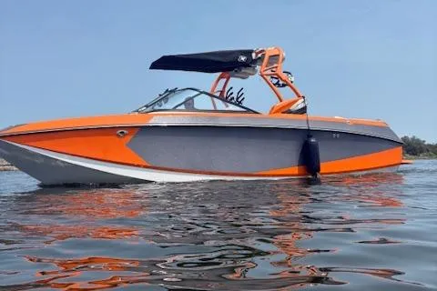 Slide: The Image of 2013 Nautique Super Air Nautique G23 boat on water, orange and gray design, sunny day. - 1