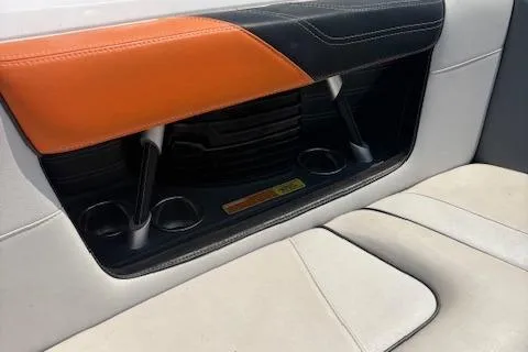 Slide: The Image of 2013 Nautique Super Air Nautique G23 interior with orange and black accents, cup holders. - 12