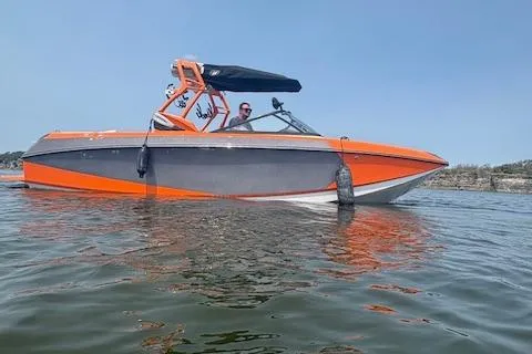 Slide: The Image of 2013 Nautique Super Air Nautique G23 boat in water, orange and gray design, sunny day. - 2