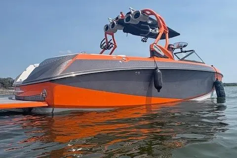 Slide: The Image of 2013 Nautique Super Air Nautique G23 boat in water, orange and gray design, wakeboard tower. - 3