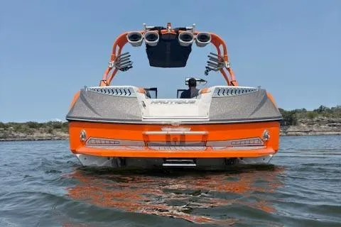 Slide: The Image of 2013 Nautique Super Air Nautique G23 boat on water, rear view, orange and gray design. - 5