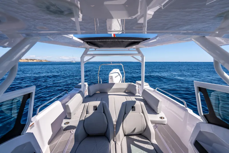 Slide: The Image of 2025 Axopar Sun-Top boat with cushioned seating and sleek design at a dock. - 17