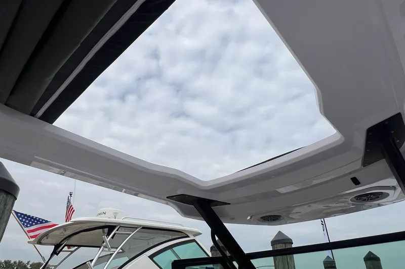 Slide: The Image of 2025 Axopar Sun-Top boat with open roof, docked under cloudy sky. - 30